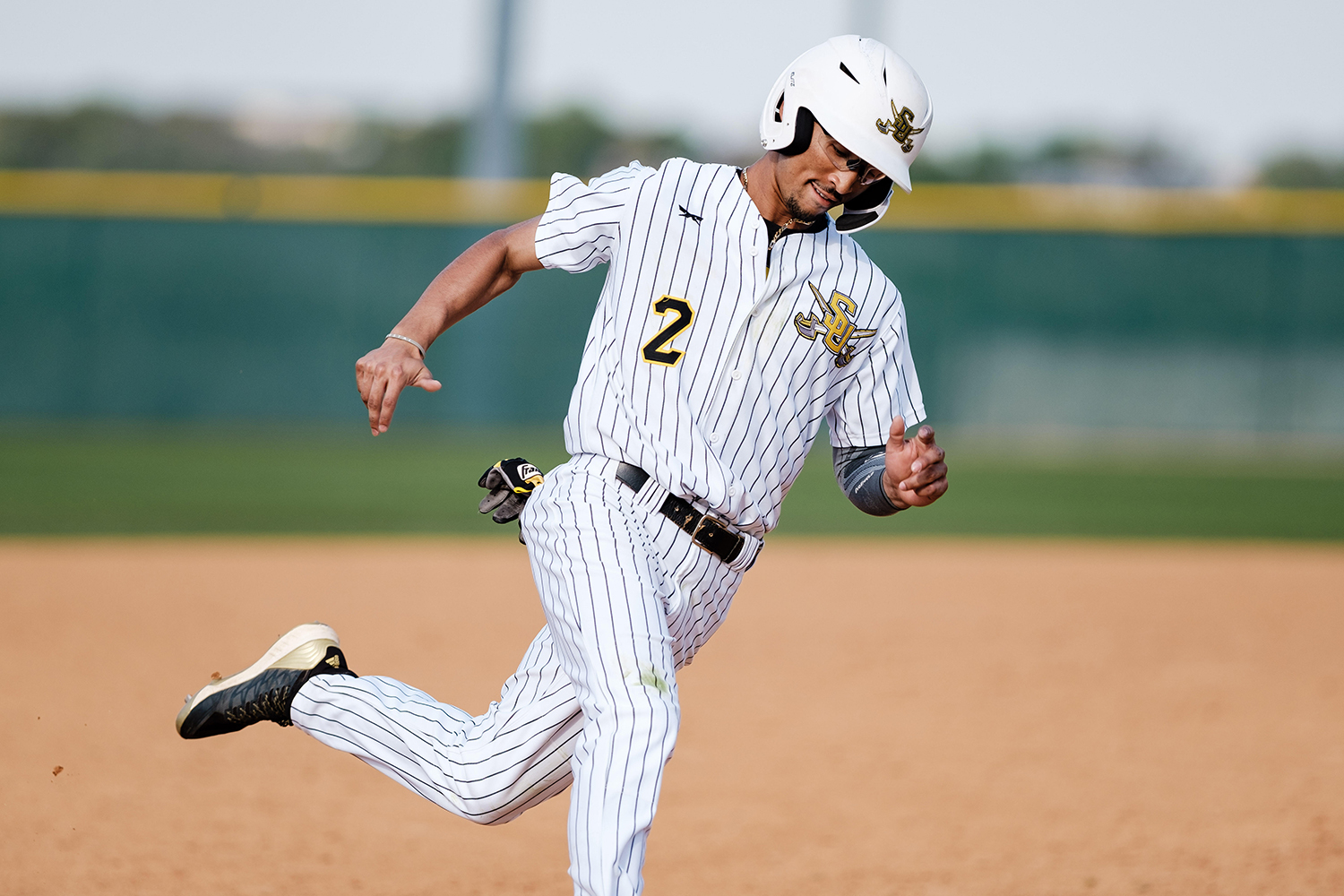 Byron Dowdell II, dressed in the Pirates white with black pinstripes uniform and white helmet, rounds third after a home run. 
