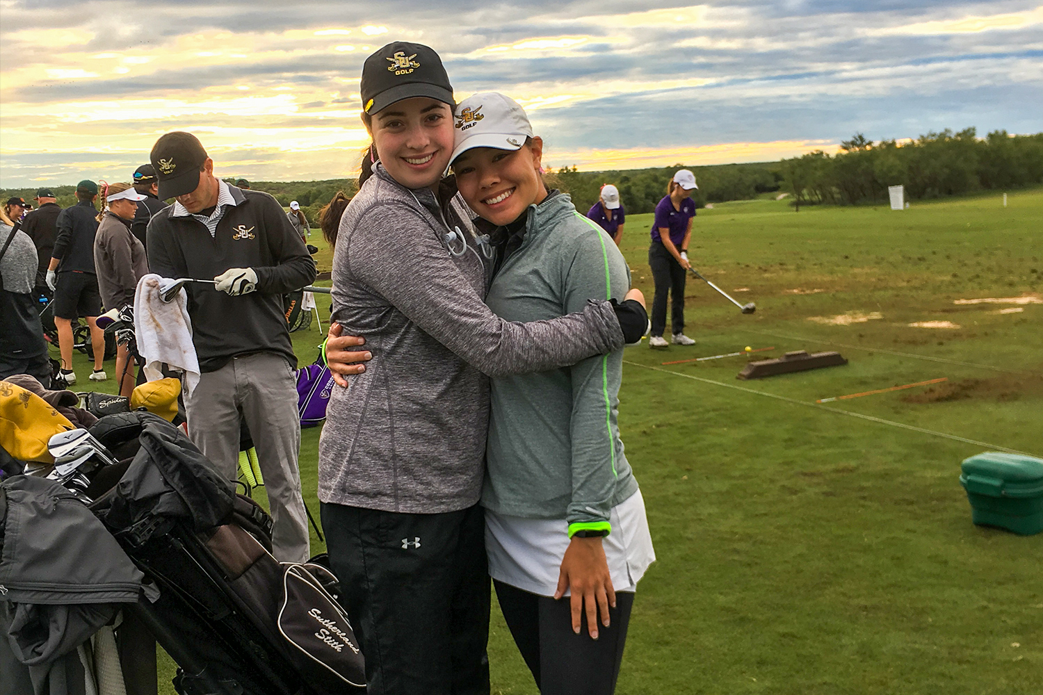 Women's golf seniors Emily Campbell and Leilani McDaniel hug each other at the driving range. 