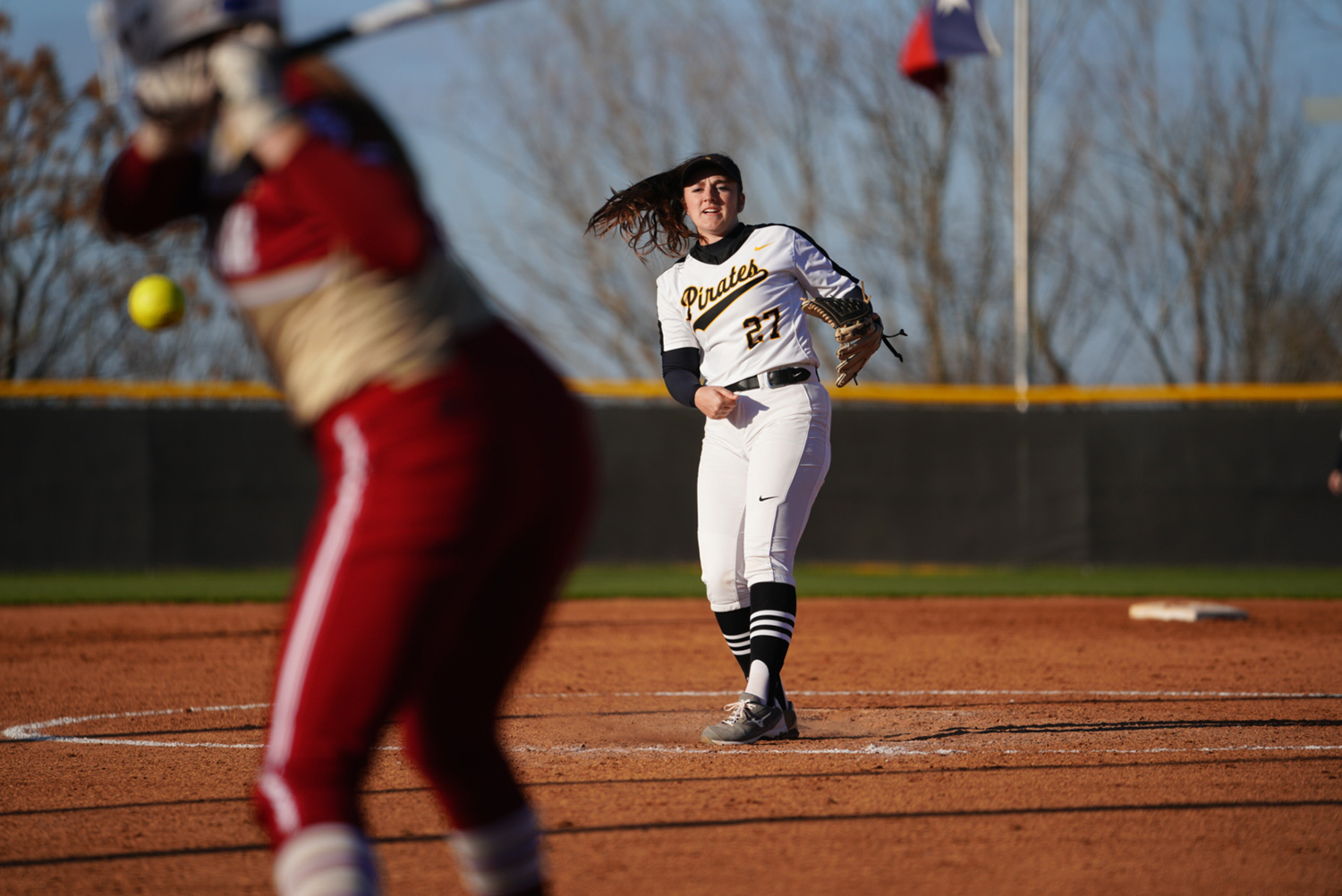 Southwestern University Pirates pitcher Lindsey Longuet, in the center of the picture, delivers a pitch against an Austin College left-handed batter, pictured to the left. 